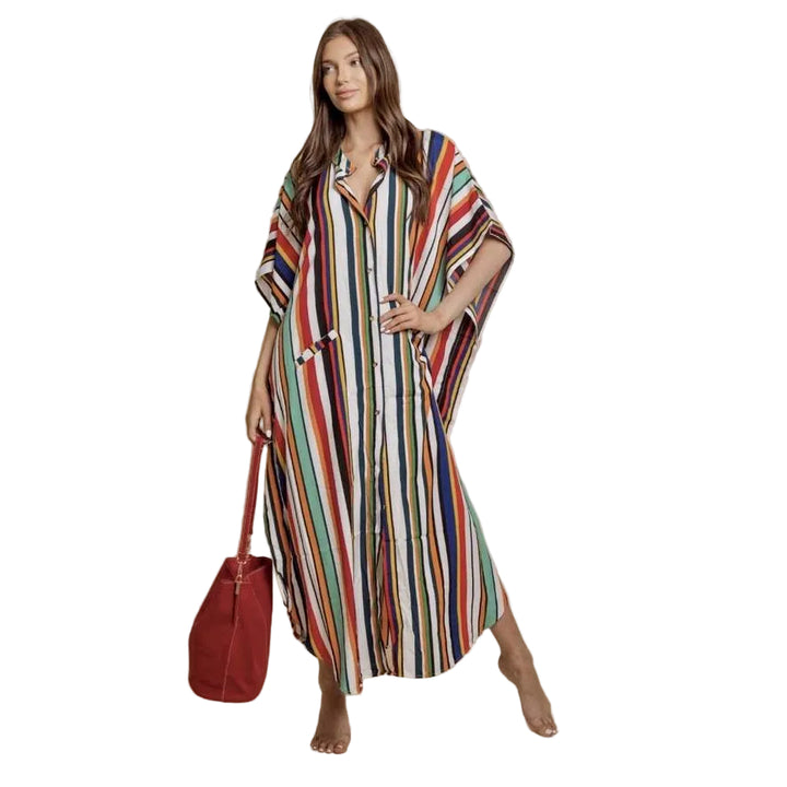 Woman wearing a long, multicolored striped dress holding a red bag against a beige background