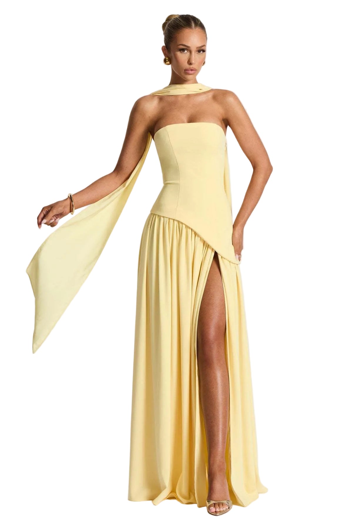 Woman wearing a yellow strapless gown with a slit on a white background