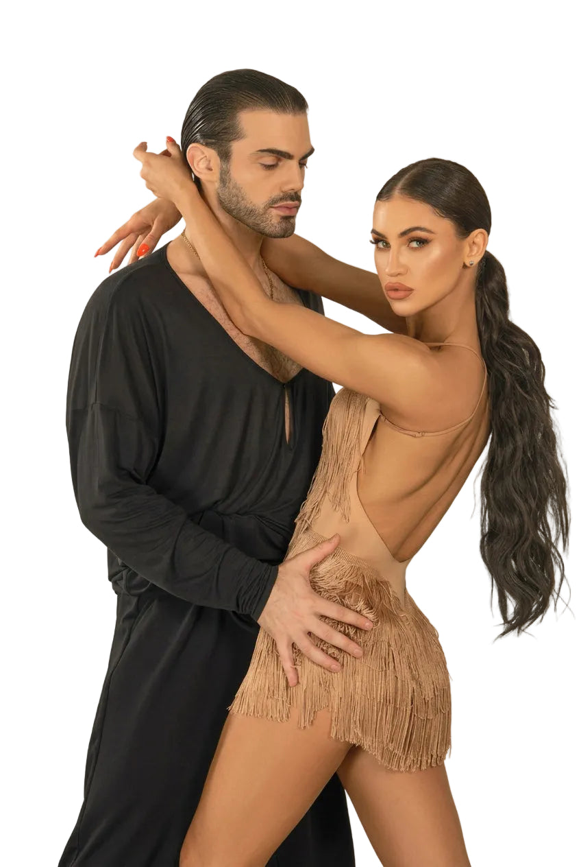 A man in a black long-sleeve shirt and a woman in a beige fringed backless mini dress pose together in an indoor studio setting.