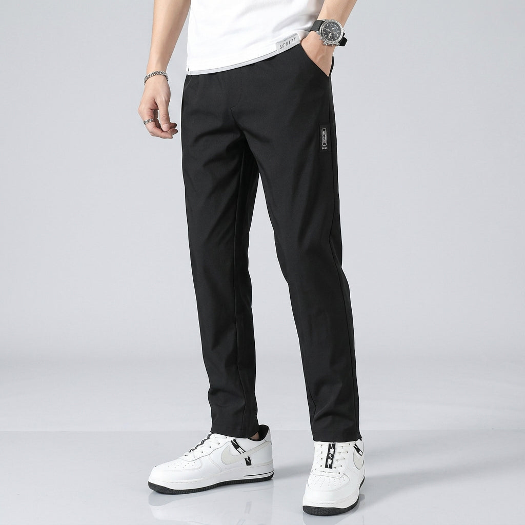 Person wearing black pants and white shoes against a gray background