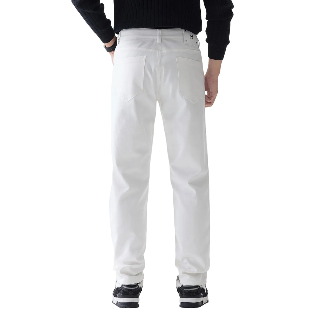 A person shown from the back wearing white straight-leg jeans, a black ribbed long-sleeve top, and black-and-white sneakers against a clean white studio background.