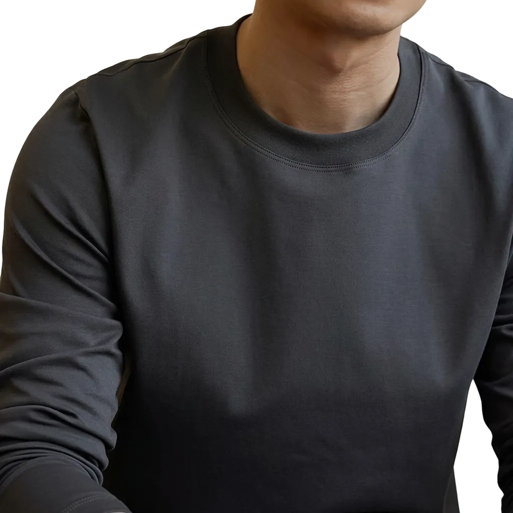 A close-up of a person wearing a dark charcoal gray long-sleeve crewneck shirt, showing the fabric texture and fit on the chest and shoulder.