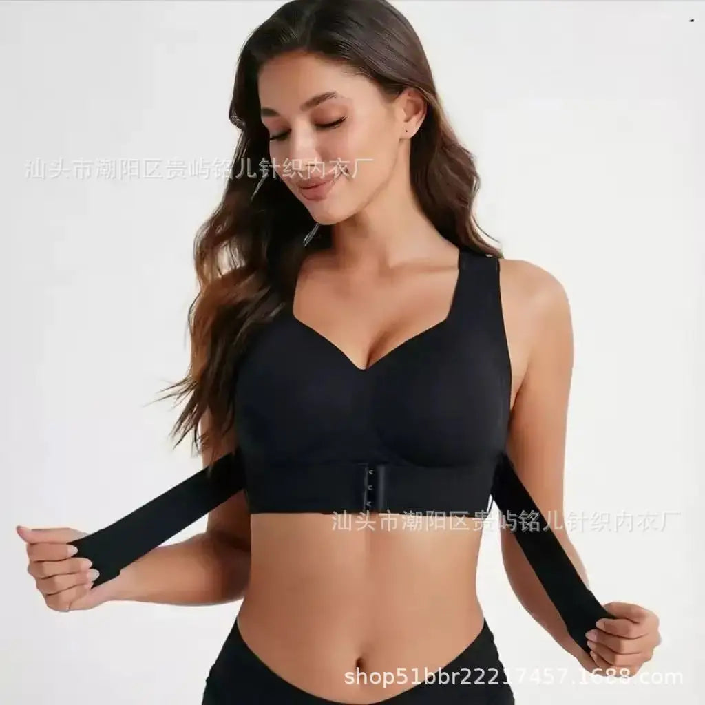 A woman modeling a black underwire bra with wide shoulder straps and a central hook-and-eye closure, shown against a plain light background.