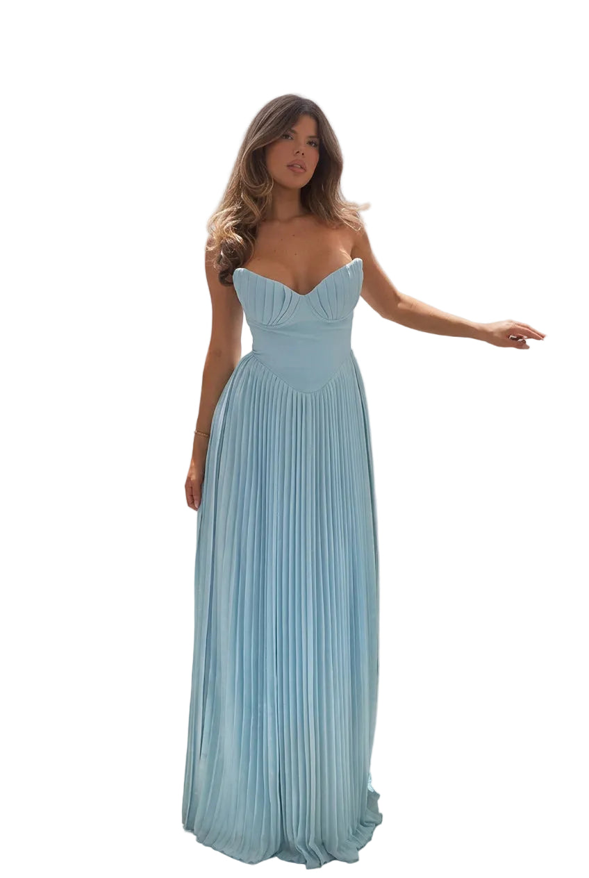 Woman in a light blue dress standing on a balcony with ocean view