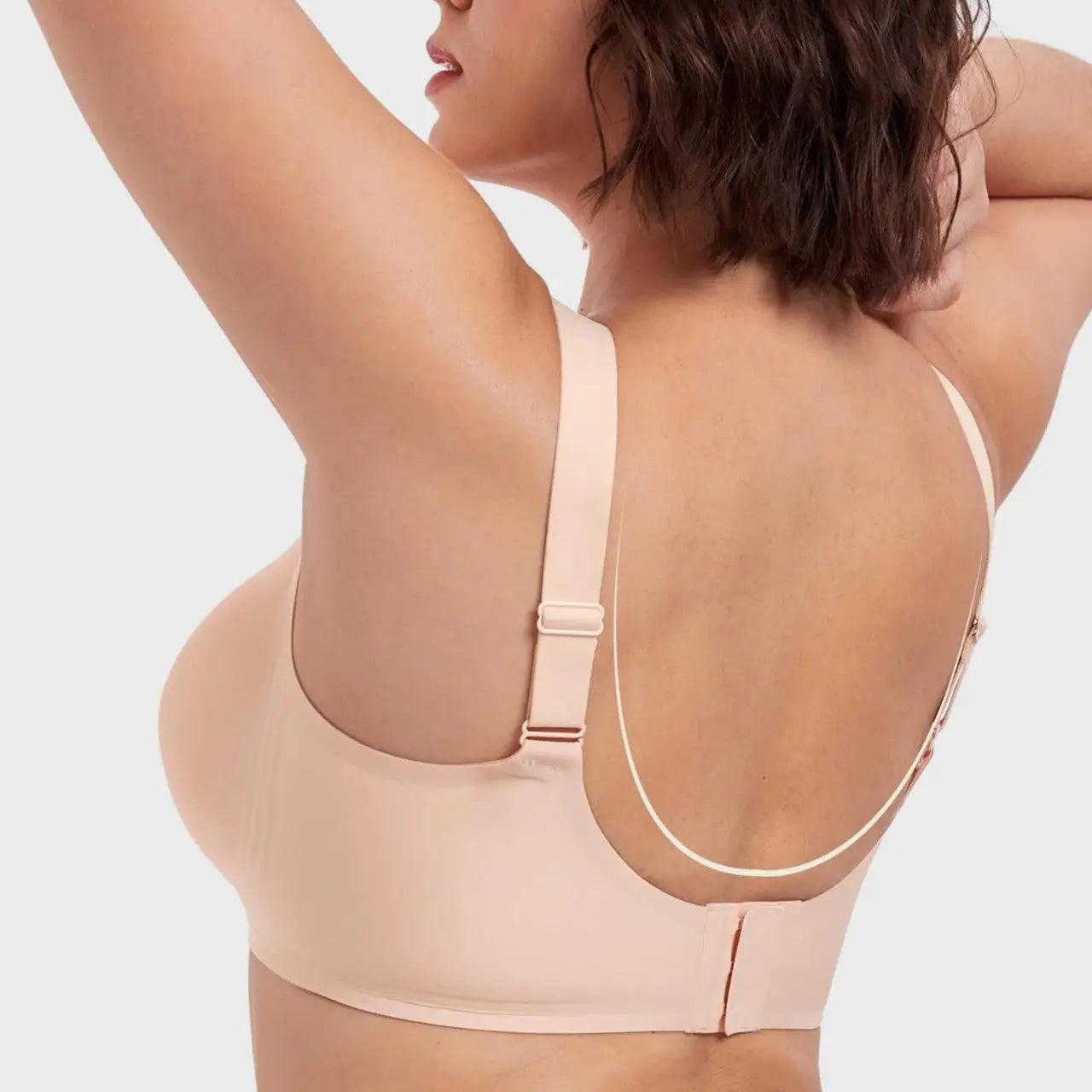 Woman wearing a beige bra against a light background