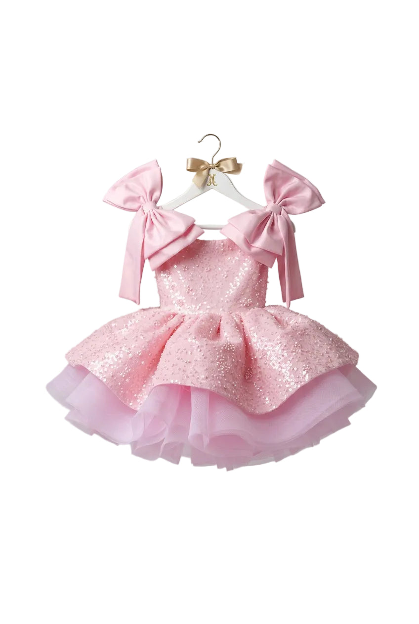 Pink dress with large bows in a white wardrobe.