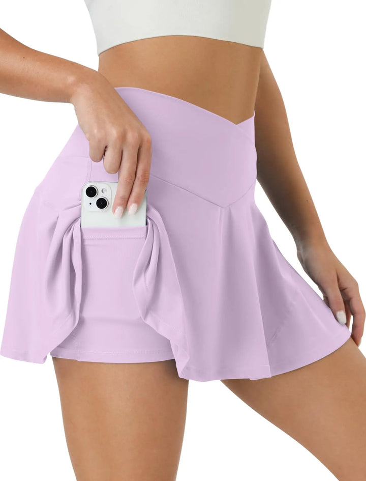 Person wearing a light purple skirt with a pocket holding a phone on a white background