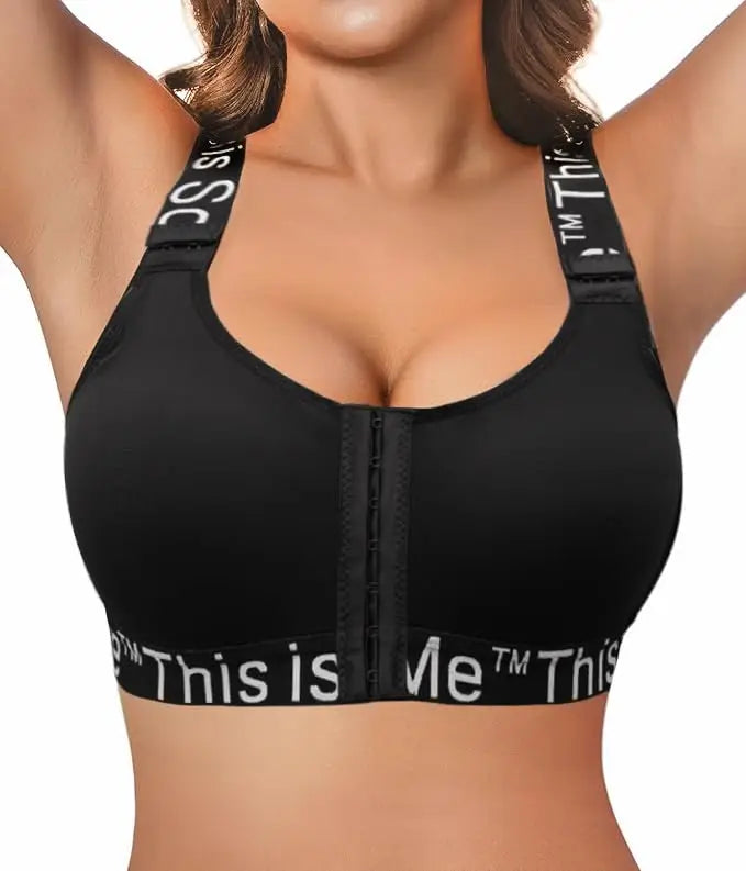 A close-up of a woman wearing a black bra with a front zipper and wide adjustable straps. The underband and shoulder straps feature white text that reads 'This is Me TM'.