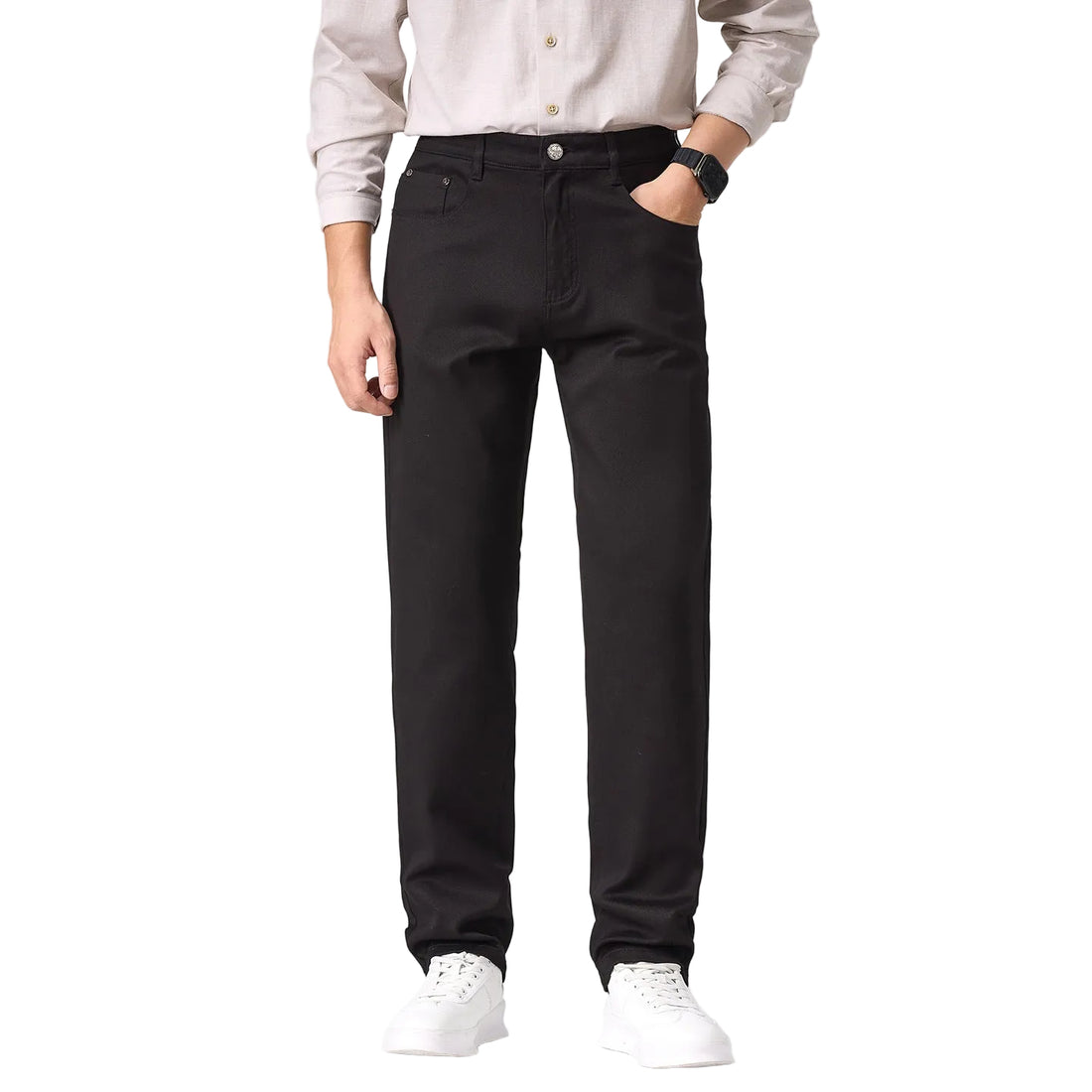 A person wearing slim-fit black straight-leg jeans, paired with a light beige button-up shirt and white sneakers, shown from the waist down against a plain white studio background.