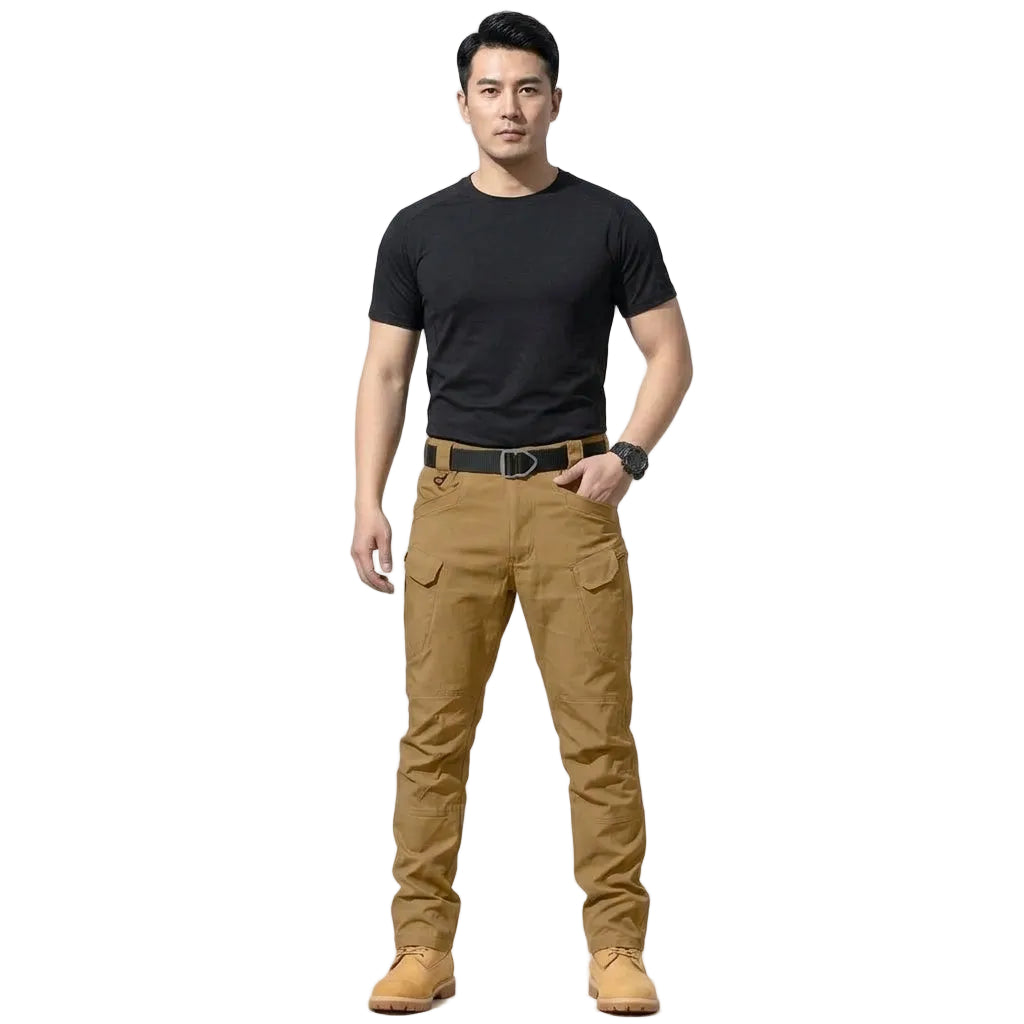 A man modeling a pair of brown cargo pants with a black t-shirt, brown belt, and tan boots against a plain white studio background.